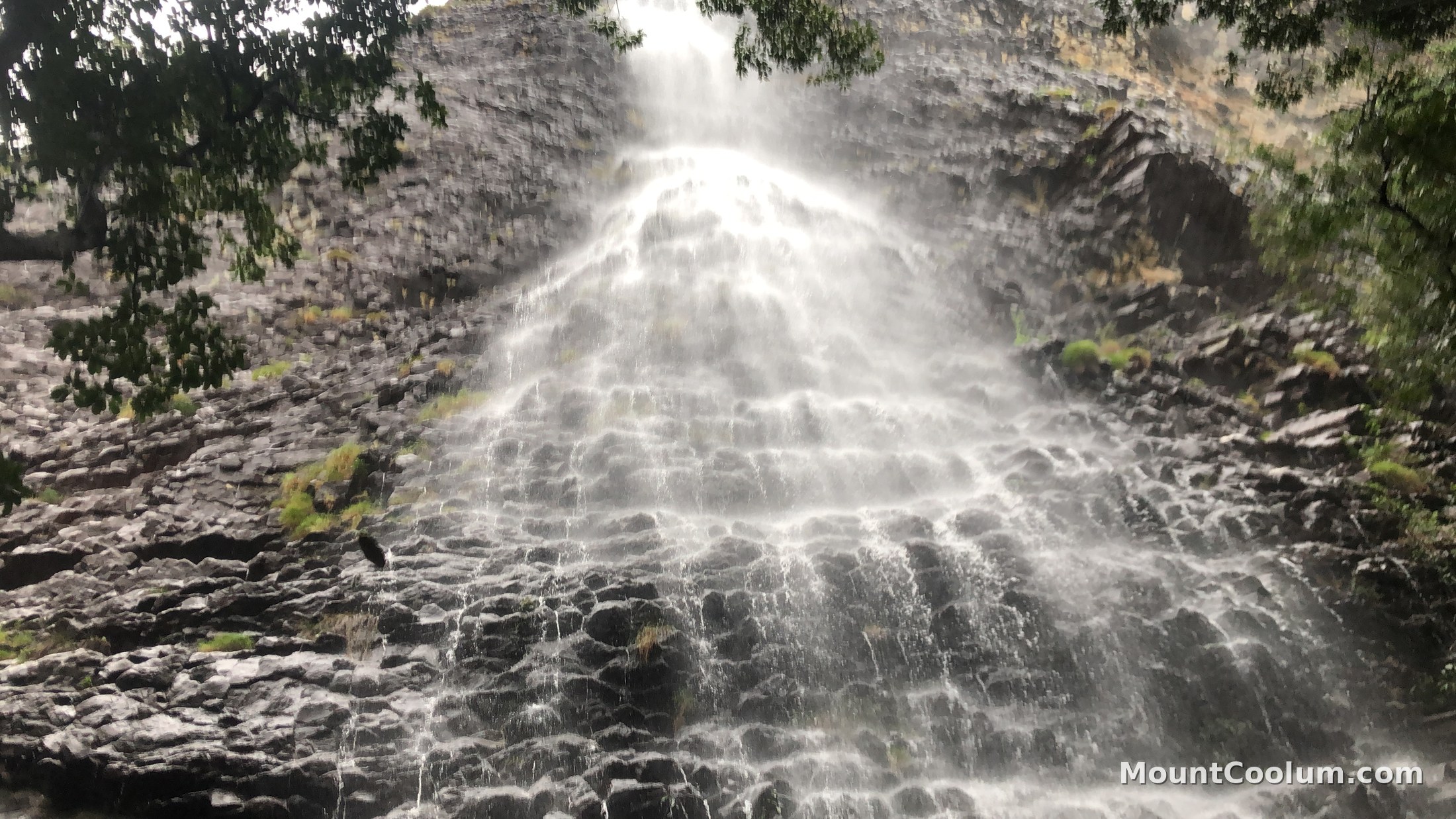 Wide view of a waterfall cascading down Mount Coolum's cliff face