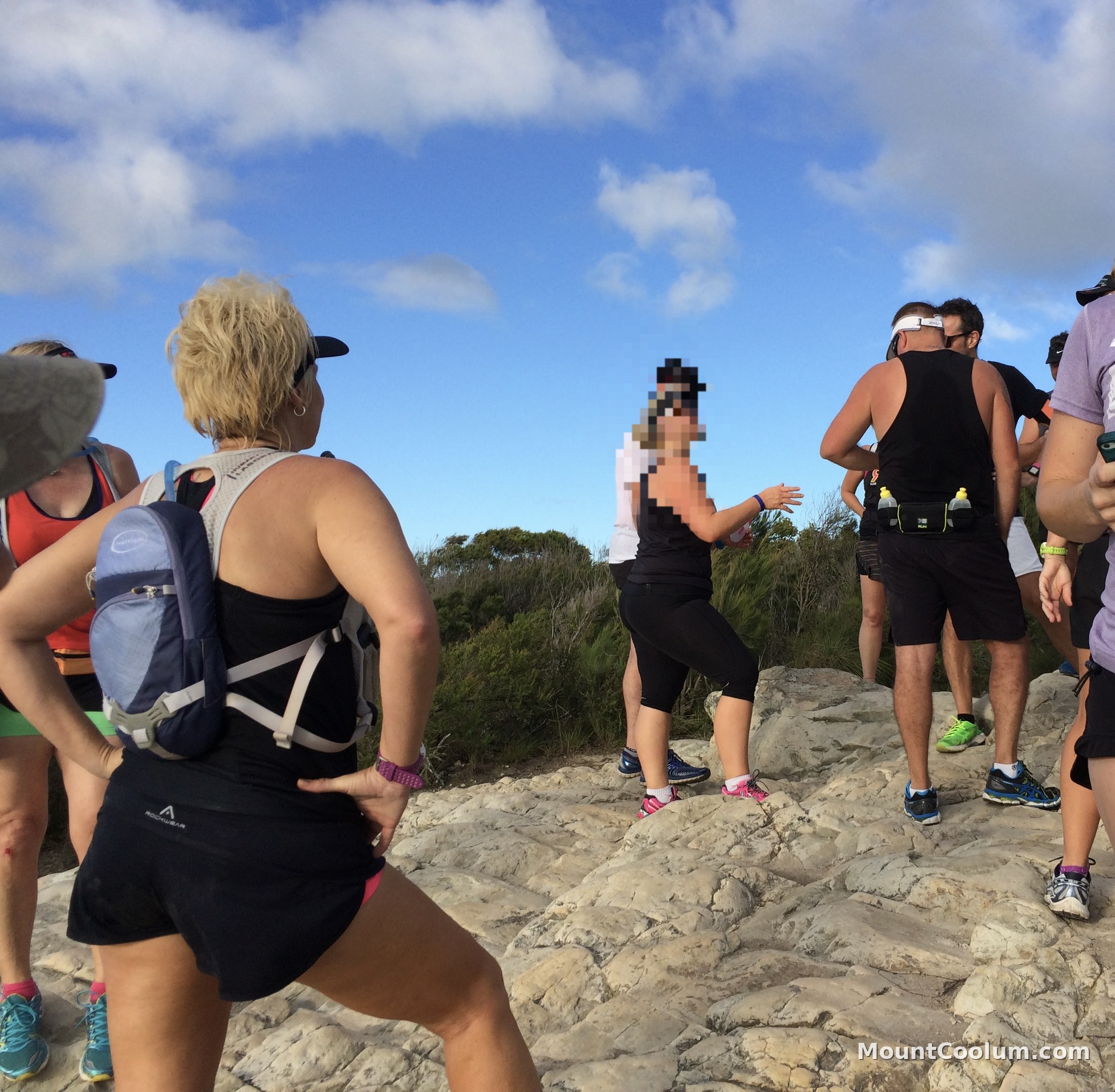 A group of walkers standing on the rocky summit outcrop of Mount Coolum after the climb
